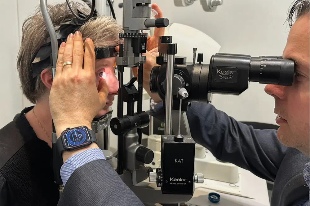 Optometrist examining a patient’s eye at a slit lamp