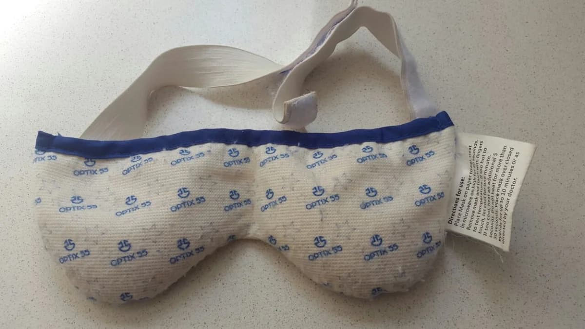 Reusable padded eye mask designed to provide a warm compress over closed eyelids