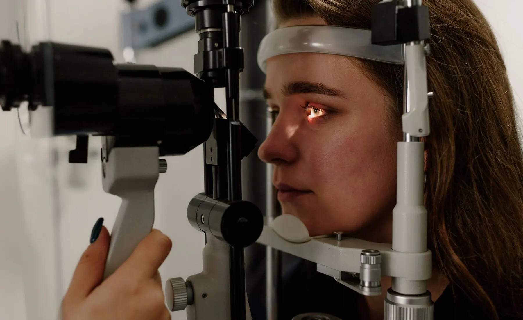 Patient looking into a slit lamp while the eye is examined