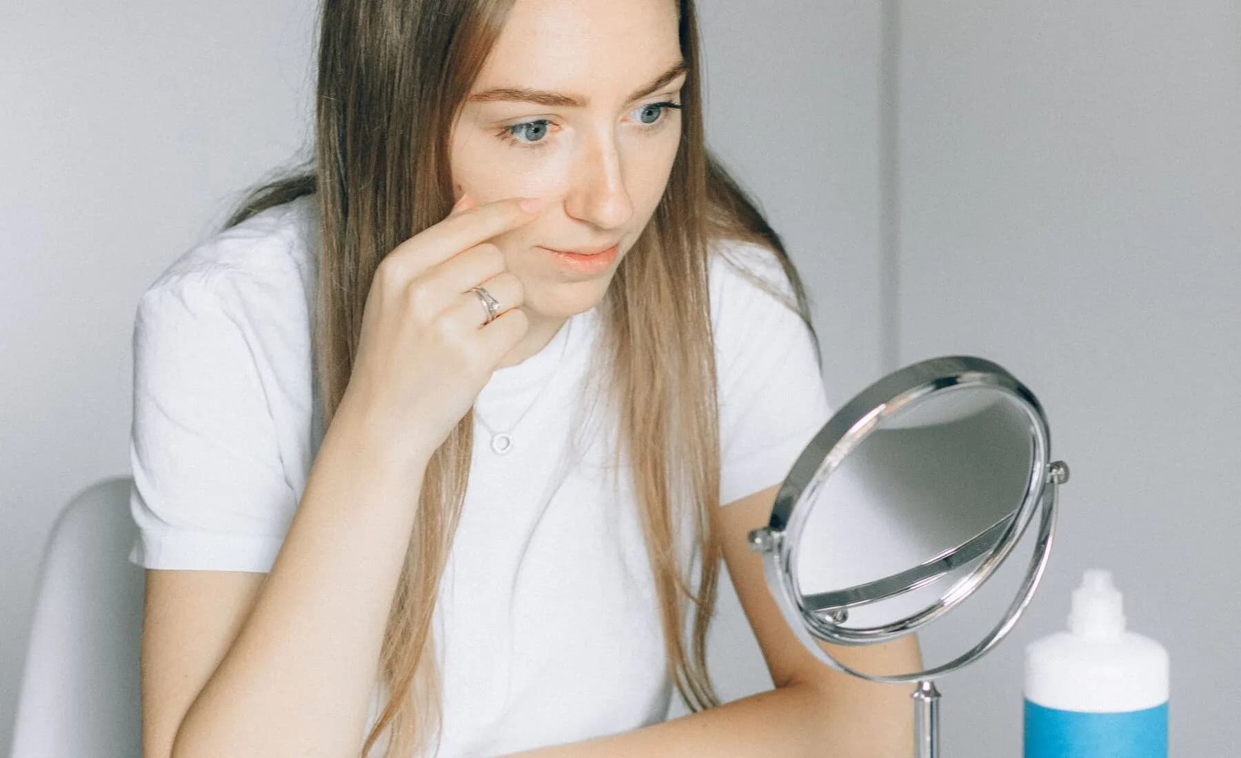 Woman looking into a mirror while preparing to insert a soft contact lens