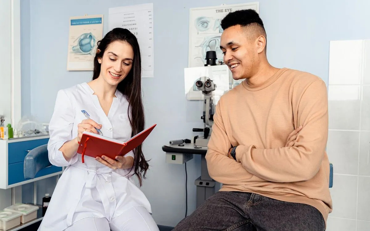 Optometrist taking notes while a patient describes his symptoms