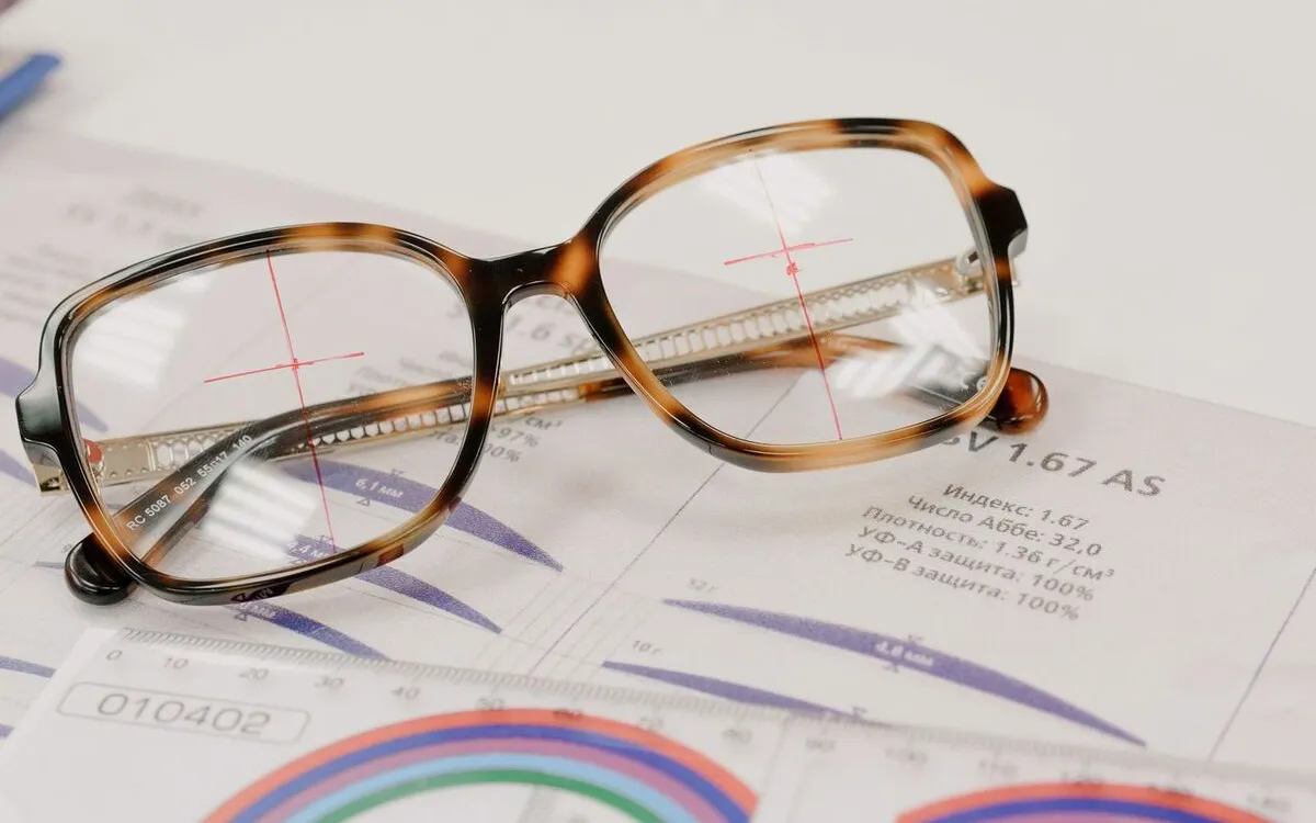 Prescription glasses resting on printed lens paperwork